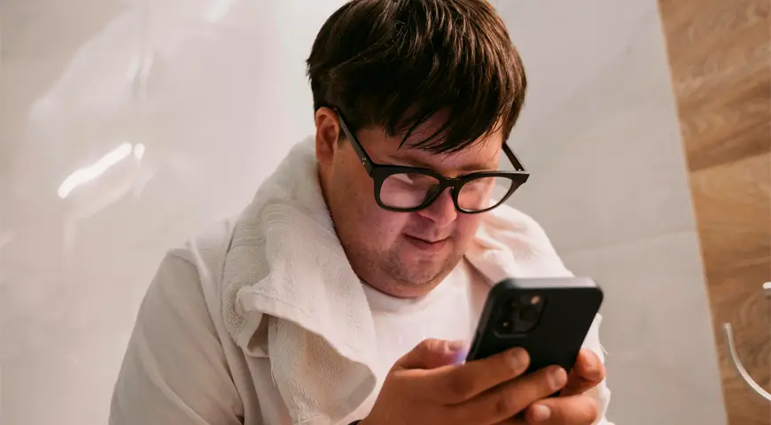 Joven con síndrome de Down viendo un celular para ilustrar nota sobre accesibilidad digital