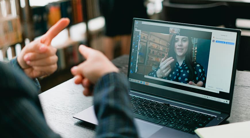 Una persona frente a un computador se comunica con otra virtualmente en lengua de señas usando una de las herramientas de la accesibilidad digital